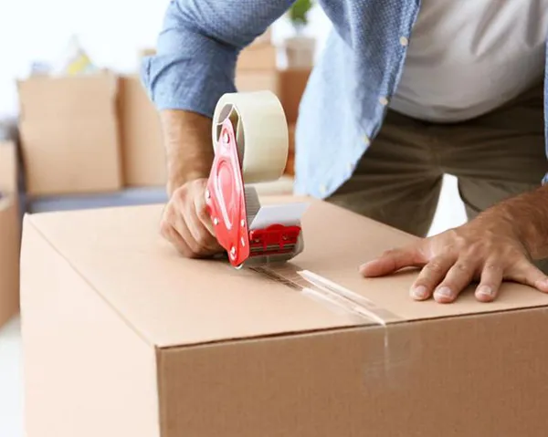 Professional mover carefully packing a cardboard box.