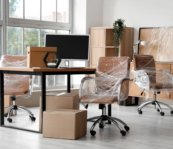 Office with unpacked desk, chairs, and scattered moving boxes.