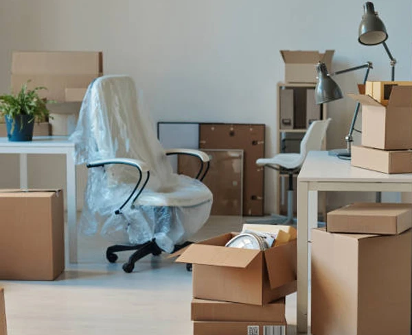 Office space with wrapped furniture and numerous cardboard boxes