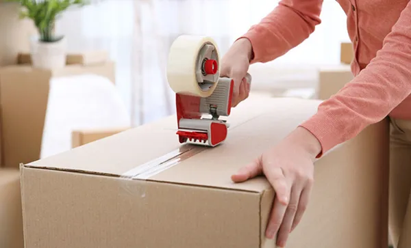 Movers packing boxes in a home, illustrating professional residential packing services.