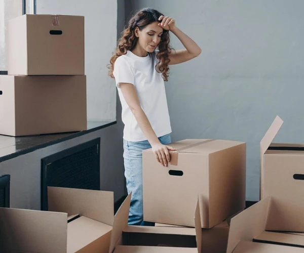 Woman overseeing packed boxes in an office environment.