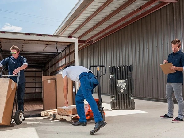 Movers unloading boxes from a truck near a house.